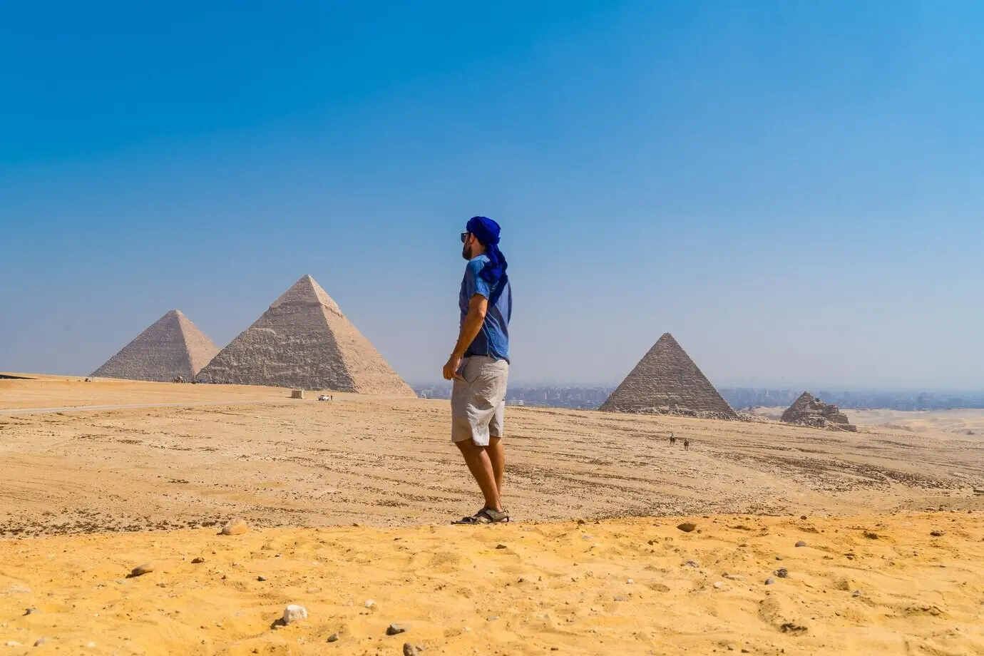Porträt eines jungen Mannes in einem blauen Turban, der an den Pyramiden von Gizeh in Kairo, Ägypten, entlanggeht.